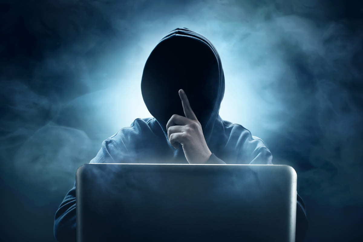 パソコンを見ているフードかぶった男性
